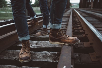 两个穿着棕色鞋子的人站在火车铁轨上